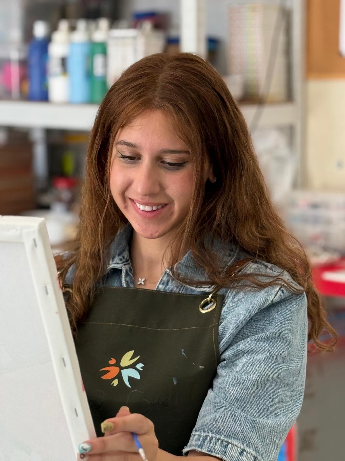 מיכל כרמי בסטודיו שלה, עם סביבת העבודה מאחוריה